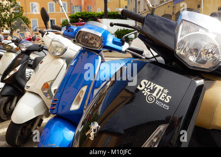 a line of scooters parked in a street in St Tropez, front scooter has 'Sixties' logo on the front. Stock Photo