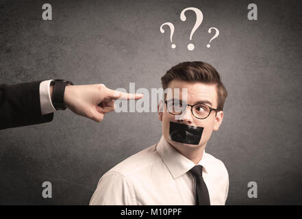 Caucasian business hand pointing at scared employee with big white question marks above his head Stock Photo