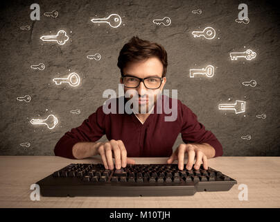 A young internet geek working online, hacking login passwords of social media users concept with glowing drawn keys on the wall Stock Photo