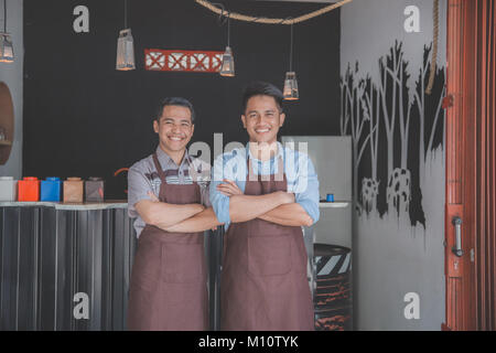 Successful two business owner proudly standing in front of their cafe Stock Photo