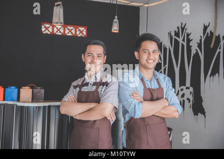 Successful two business owner proudly standing in front of their cafe Stock Photo