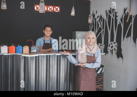 muslim waiter welcoming customer to come to their newly open cafe Stock Photo