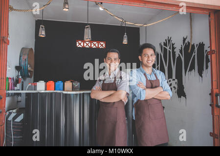 Successful two business owner proudly standing in front of their cafe Stock Photo