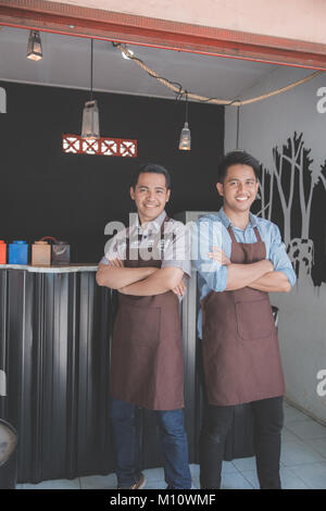 Successful two business owner proudly standing in front of their cafe Stock Photo