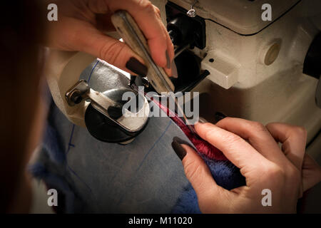 Close op of sewing process of the female fur coat on sewing machine . Stock Photo