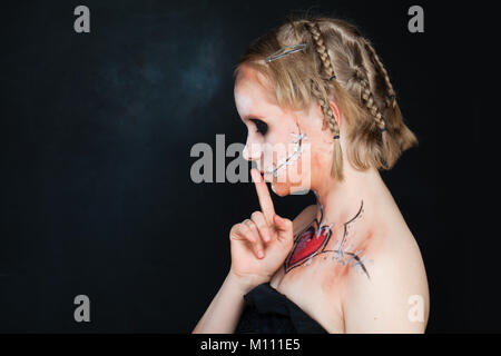 Young Girls with Love Makeup Holding her Finger to her Lips in a Gesture for Silence. Secret, Silent and Shushing Stock Photo