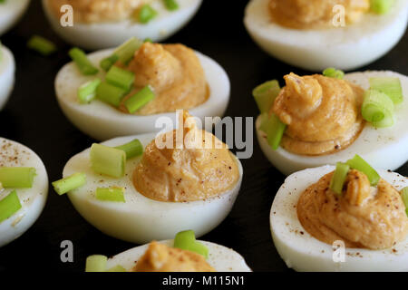 Deviled eggs with cod livers with leek on on black background Stock Photo