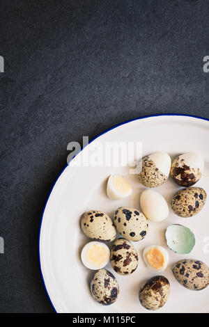 Hard boiled Quail Eggs and shells on an enamel plate on a slate background Stock Photo