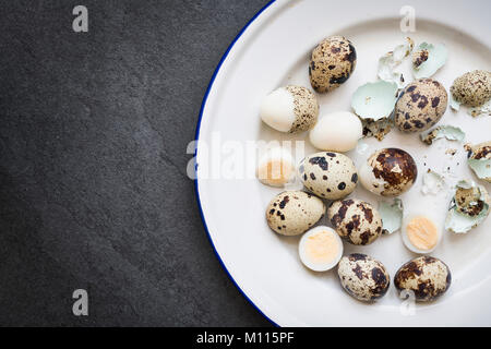 Hard boiled Quail Eggs and shells on an enamel plate on a slate background Stock Photo