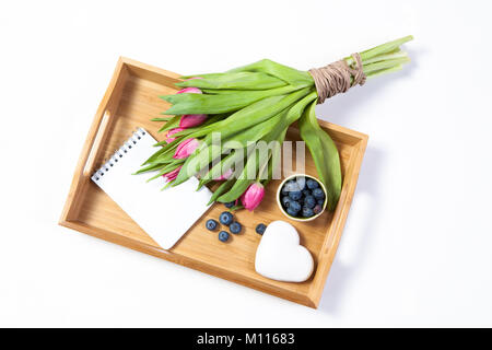 A tray with tea and gingerbread in the shape of heart and a bouquet of tulips on the chair Stock Photo