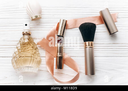 luxury make up essentials brush and lipstick and perfume flat lay on white rustic wooden table with space for text in soft morning light. fashion blog Stock Photo