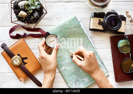 wanderlust and travel concept flat lay. hand holding compass and pencil on map exploring. passport money glasses photo camera on white wooden backgrou Stock Photo