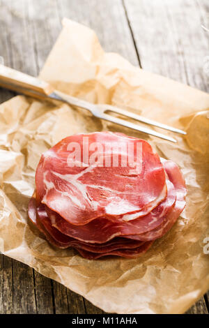 Sliced prosciutto crudo on paper. Stock Photo