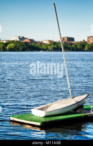 Boston Charles River small sailboat in the foreground. Beacon Hill historic red brick buildings are seen across the water Stock Photo
