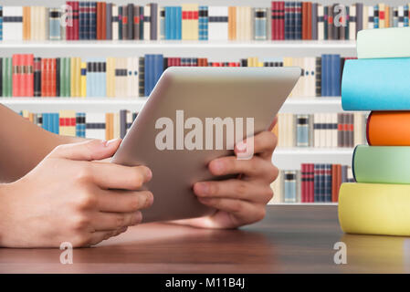 Close-up Of Hand Holding Digital Tablet On Table In The Library Stock Photo