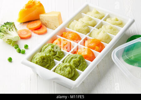 Pureed baby food in ice cube trays ready for freezing on white wooden table Stock Photo