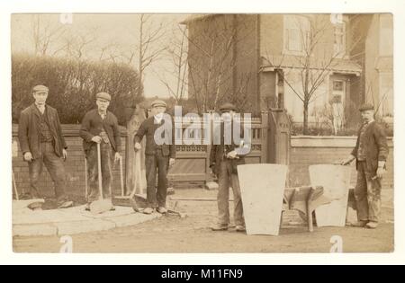 Original postcard of gang of Edwardian workmen, navvies, builders outside house, wearing working clothes and flat caps, holding their work tools, working on a pavement, road building, circa 1910, U.K. Stock Photo