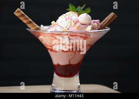 beautiful food photography image of a bright red and white strawberry ice cream sundae in a glass with black background for a summer time day Stock Photo