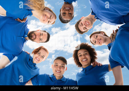Low Angle View Of Smiling Multiracial Janitors Forming Huddle Stock Photo