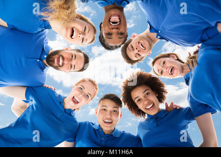 Low Angle View Of Smiling Multiracial Janitors Forming Huddle Stock Photo
