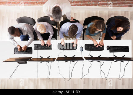 Elevated View Of Male Teacher Assisting Students In Computer Room Stock Photo