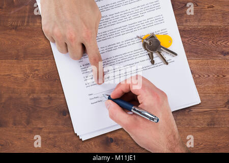 High Angle View Of A Real Estate Agent's Hand Helping Client In Filling Contract Form Stock Photo