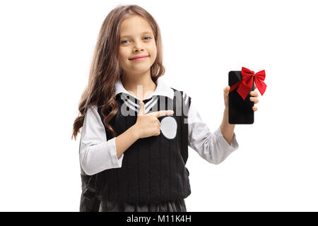 Little schoolgirl holding a phone wrapped with a red ribbon as a present and pointing isolated on white background Stock Photo