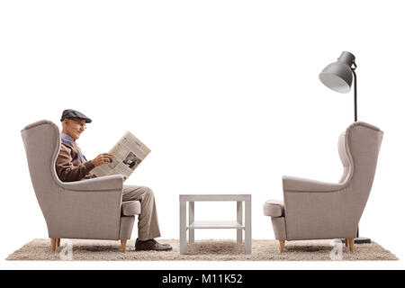 Senior sitting in an armchair and reading a newspaper isolated on white background Stock Photo