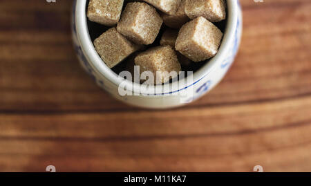 Photography with Kitchen Theme: Still Life with Brown Lump Sugar in Ceramic Bowl on Wooden Cutting Board. Stock Photo