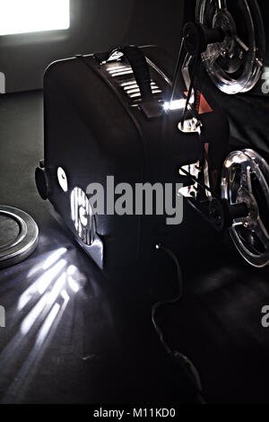 Old film projector and a glowing screen in the dark Stock Photo