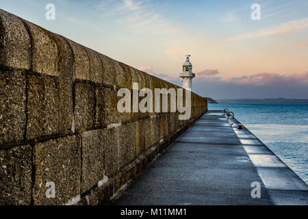 Mevagisseys routinley battered, sea facing harbour wall protecting both the lighthouse and all manner of vessels within its historic walls. Stock Photo