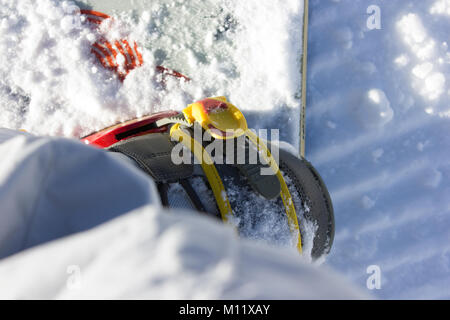 a beautiful detail photograph of snowboard bindings, snowboard boot and board covered in snow on piste Stock Photo