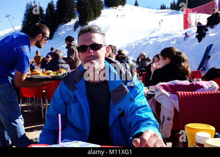 Eating in an outside ski resort restaurant on a sunny day, Samoens France Stock Photo