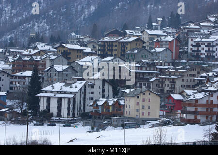 a view of the houses of skiing resort Chiesa Valmalenco, Italy with snow on roof tops from a distance Stock Photo