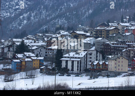 a view of the houses of skiing resort Chiesa Valmalenco, Italy with snow on roof tops from a distance Stock Photo