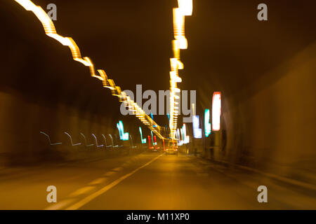 cars in motorway tunnel at night with blurred trail lights Stock Photo