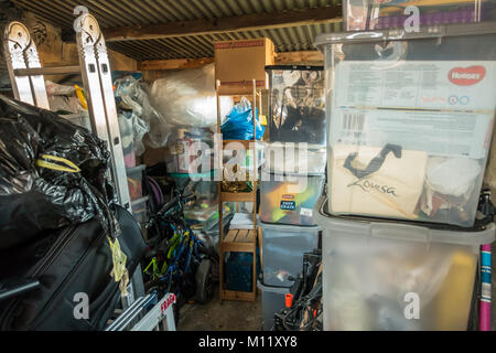Plastic storage boxes filled with belongings and clutter in a garage. Stock Photo
