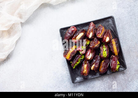 Stuffed dates with nuts and candied fruit filling on a stone or slate background. The concept of a healthy dessert. Stock Photo