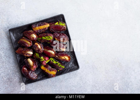 Stuffed dates with nuts and candied fruit filling on a stone or slate background. The concept of a healthy dessert. Stock Photo