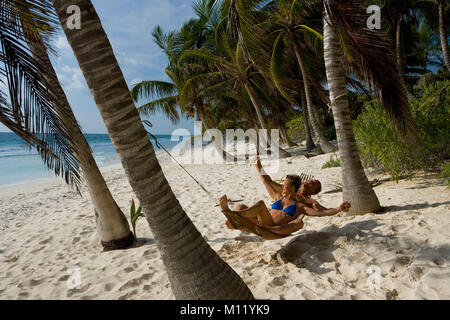 Mexico. Yucatan peninsula. Tulum. Palm trees. Couple relaxing in Hammock. Stock Photo