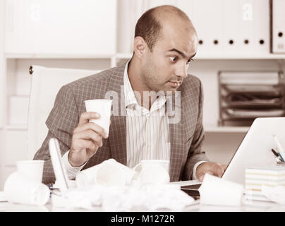 Young male having lot of work and problems in the office Stock Photo