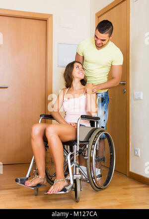 Young social worker brought smiling girl in invalid chair home Stock Photo
