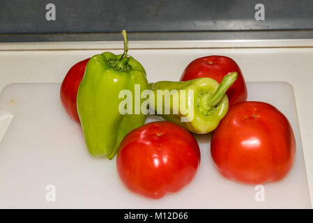 Tomatoes peppers and a knife on a plastic plate in the kitchen bench Stock Photo