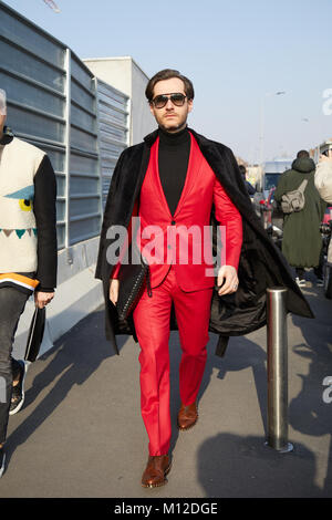 MILAN - JANUARY 14: Man with red jacket and trousers and black coat before Dsquared 2 fashion show, Milan Fashion Week street style on January 14, 201 Stock Photo