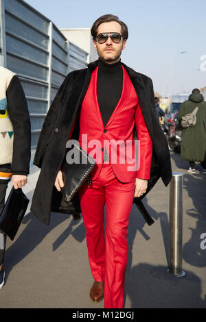 MILAN - JANUARY 14: Man with red jacket and trousers and black coat before Dsquared 2 fashion show, Milan Fashion Week street style on January 14, 201 Stock Photo