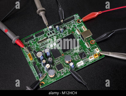 Close-up of electronic circuit board with several microchips with tools and wires around Stock Photo