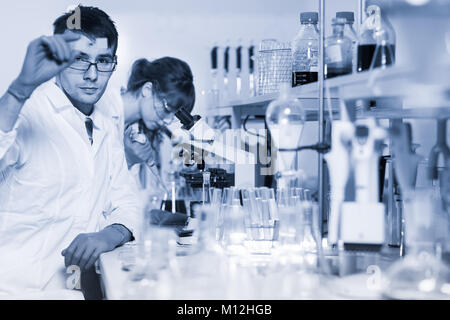 Health care researchers working in life science laboratory. Young researchs preparing and analyzing microscope slides in research lab. Stock Photo