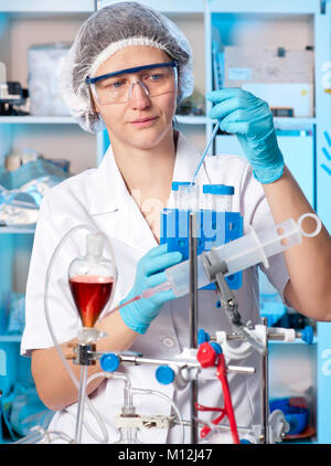 Senior female tech in protective wear works in chemical lab Stock Photo