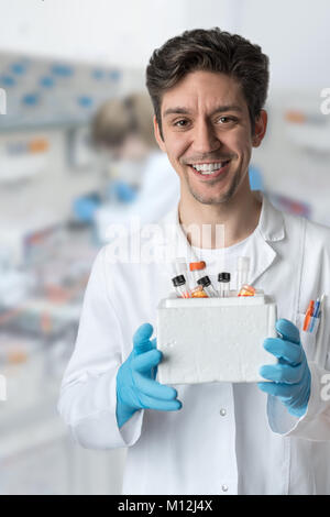Smiling male scientist with brown eyes and curly hair holds box of samples Stock Photo