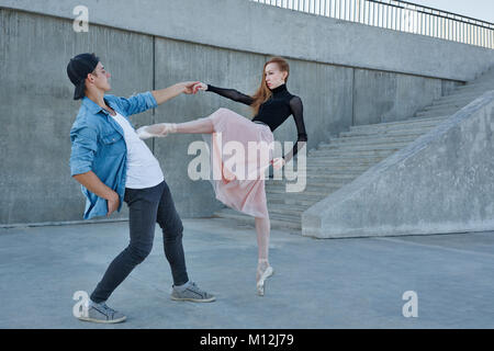 A slender ballerina dances with a modern dancer. Date of lovers. Performance in the streets of the city. Stock Photo